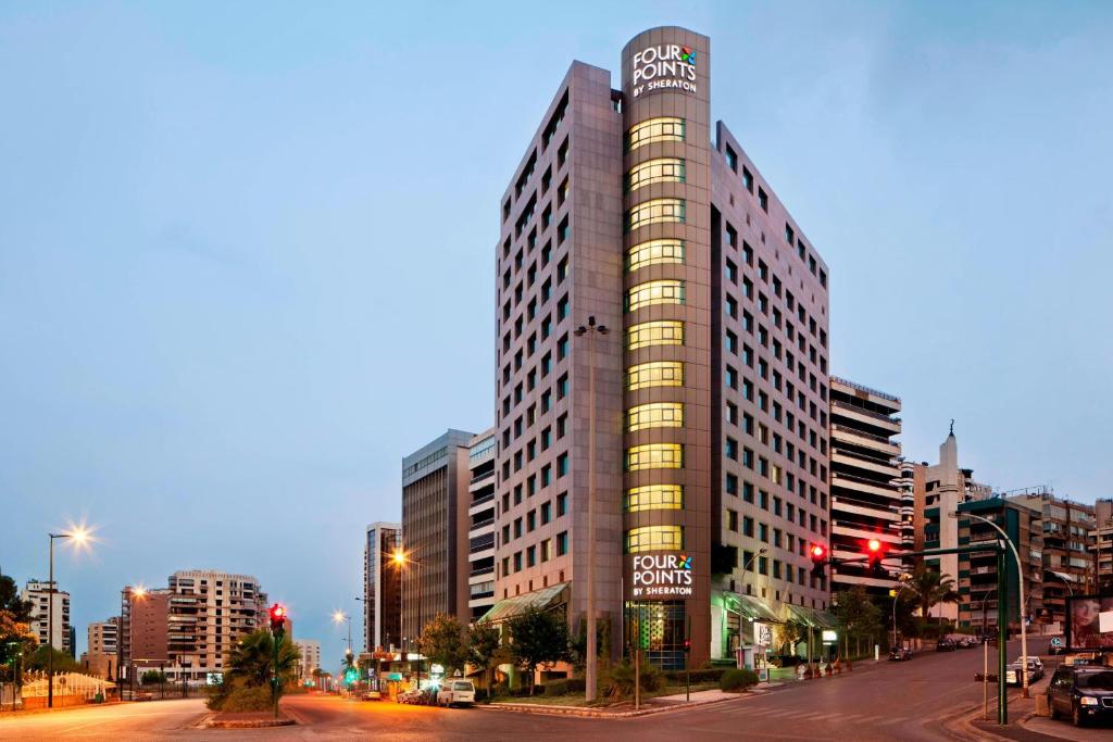 un grand bâtiment sur une rue de la ville à crépuscule dans l'établissement Four Points By Sheraton Le Verdun, à Beyrouth