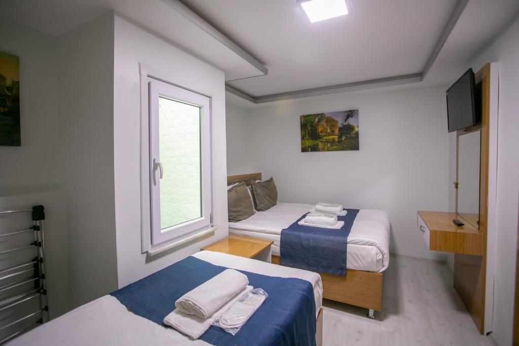 a small room with two beds and a window at Güven House İstanbul in Istanbul