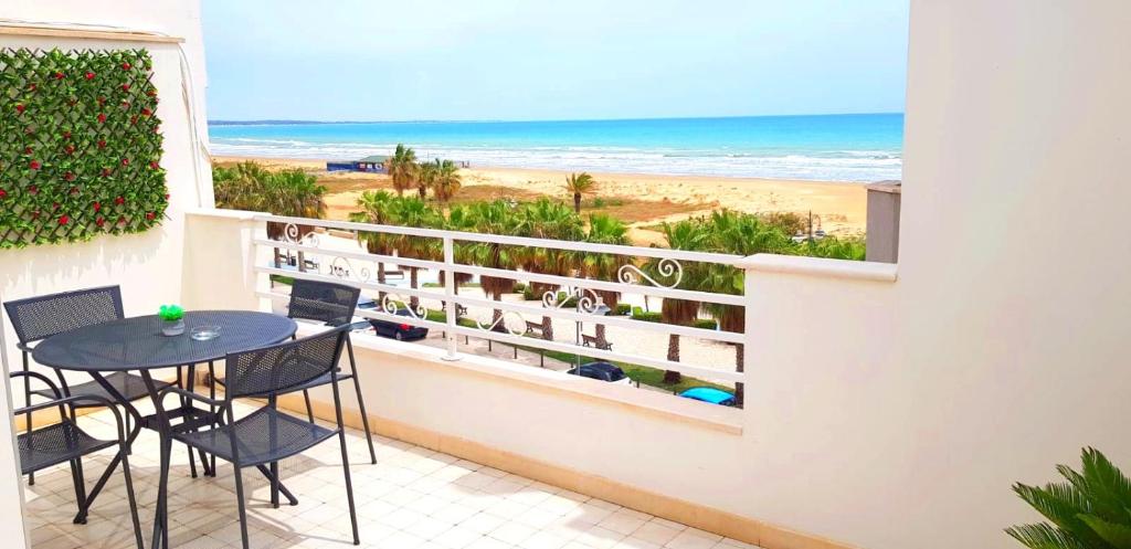 een balkon met een tafel en stoelen en het strand bij MADAGÌ Beachfront Apartments in Pozzallo