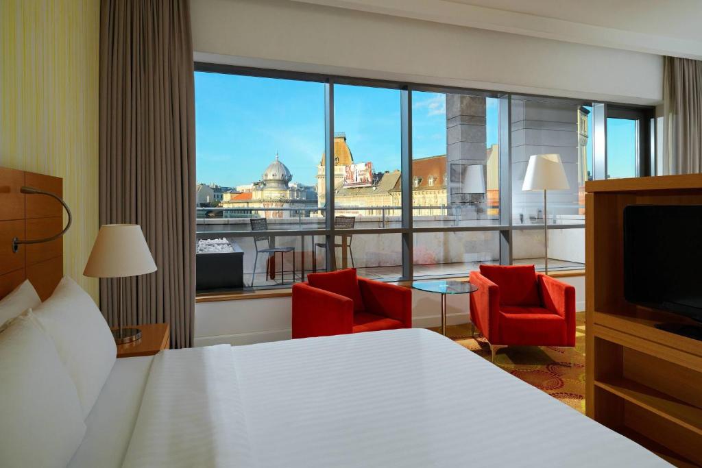 ブダペストにあるコートヤード バイ マリオット ブダペスト シティ センターのベッドと大きな窓が備わるホテルルームです。