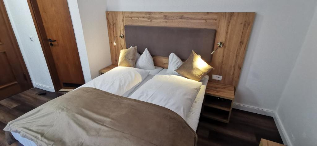 Schlafzimmer mit einem Bett mit weißer Bettwäsche und goldenen Kissen in der Unterkunft Heidehotel Soltauer Hof in Soltau