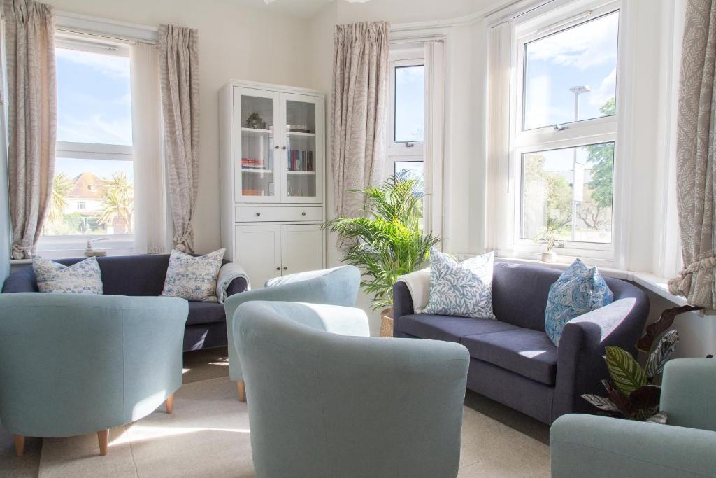 ein Wohnzimmer mit blauen Sofas und Fenstern in der Unterkunft Harry's House Poole in Poole