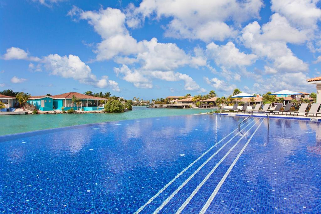 a large swimming pool with blue water and houses at Courtyard by Marriott Bonaire Dive Resort in Kralendijk
