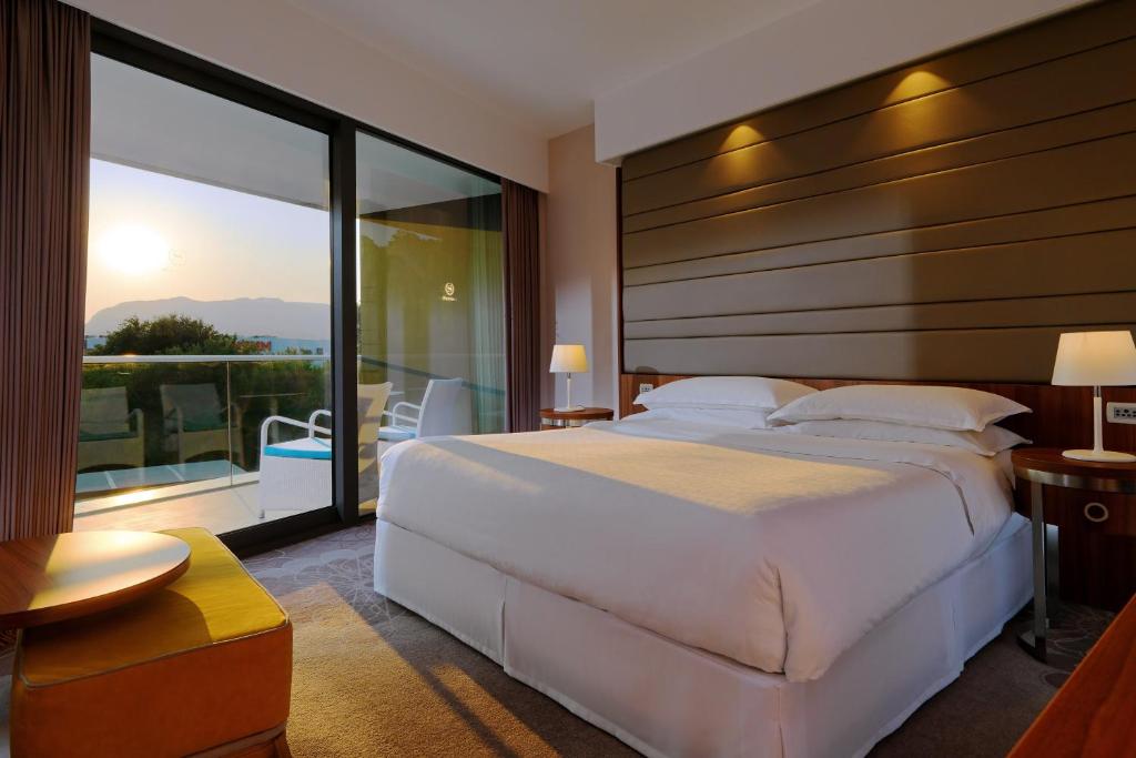 a bedroom with a large white bed and a balcony at Sheraton Dubrovnik Riviera Hotel in Mlini