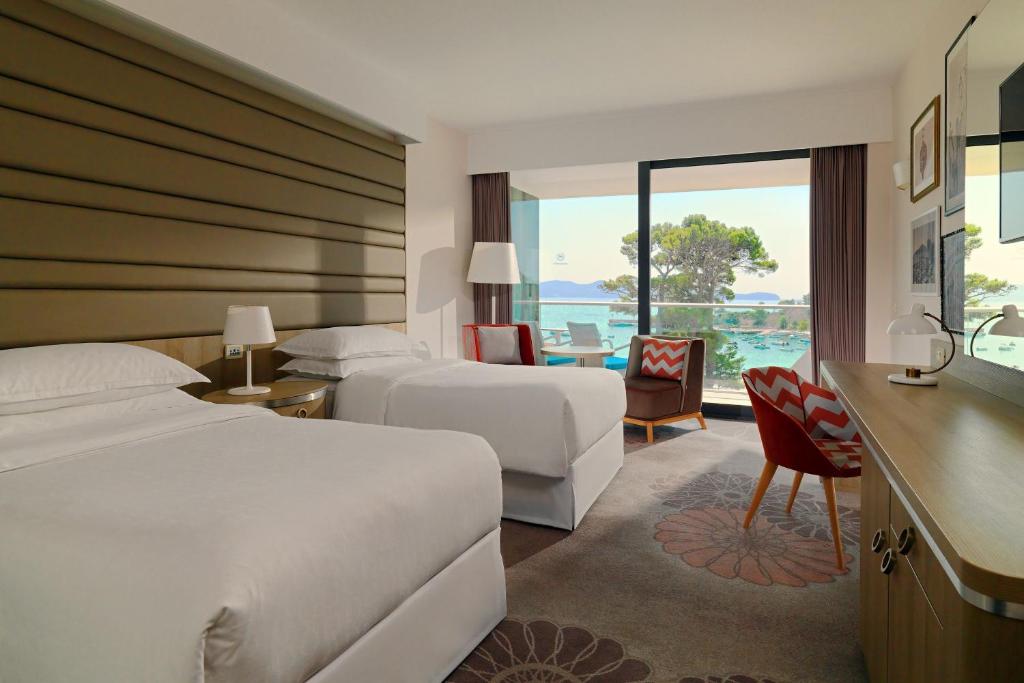 a hotel room with two beds and a desk at Sheraton Dubrovnik Riviera Hotel in Mlini