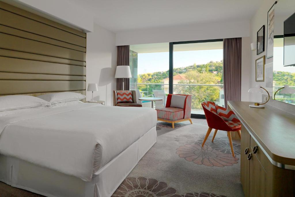a bedroom with a large white bed and a desk and chair at Sheraton Dubrovnik Riviera Hotel in Mlini