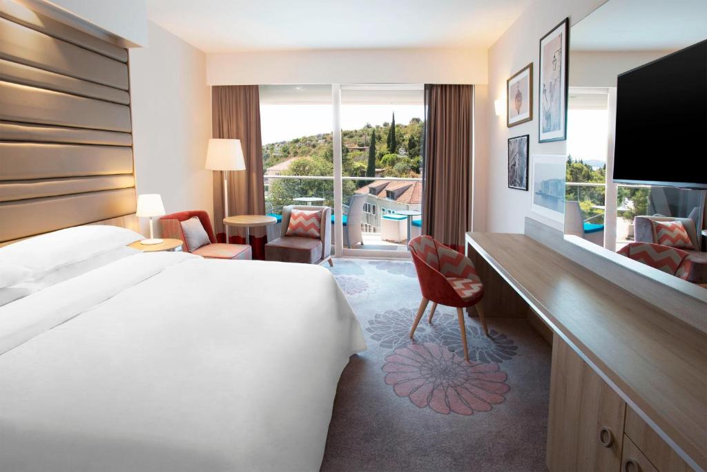 a hotel room with a bed and a desk and a window at Sheraton Dubrovnik Riviera Hotel in Mlini