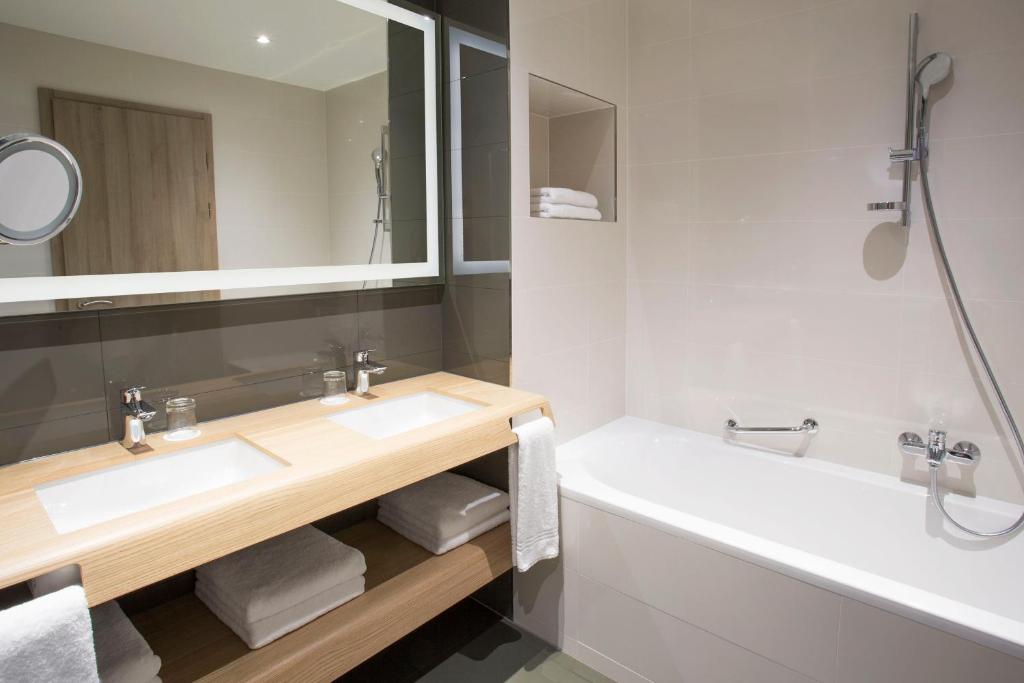 a bathroom with a sink and a tub and a mirror at Sheraton Dubrovnik Riviera Hotel in Mlini