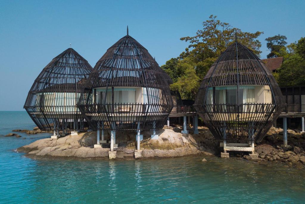 drei Häuser auf einer kleinen Insel im Wasser in der Unterkunft The Ritz-Carlton, Langkawi in Pantai Kok