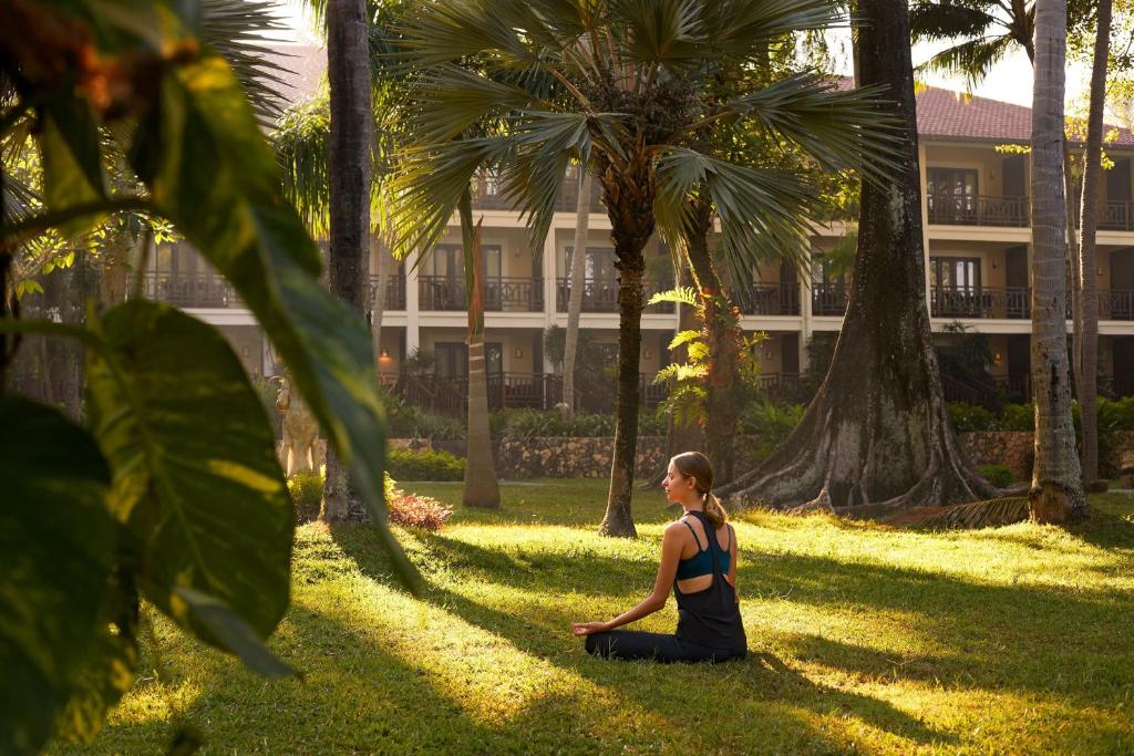 a woman sitting in the grass in a yoga pose at Sheraton Senggigi Beach Resort in Senggigi