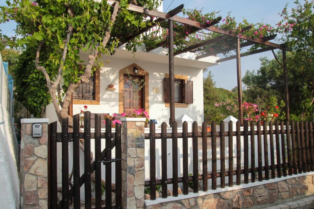 a fence in front of a small house with flowers at Villa Nefeli Rhodes in Archangelos