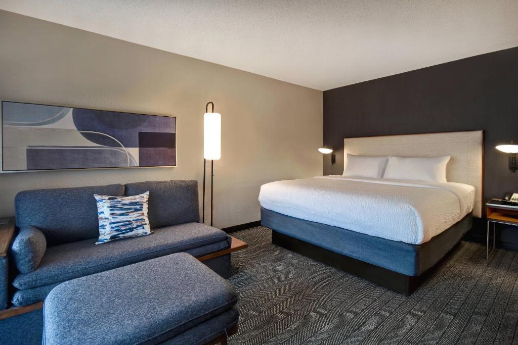 a hotel room with a bed and a chair at Courtyard by Marriott Cincinnati Airport in Erlanger