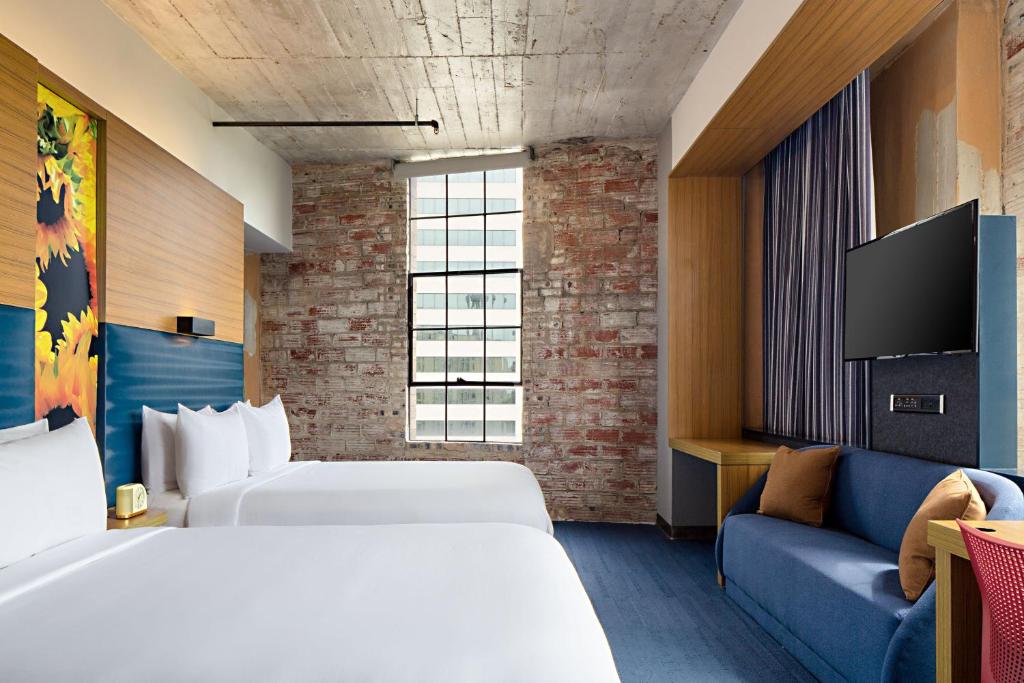 a hotel room with two beds and a couch at Aloft Dallas Downtown in Dallas