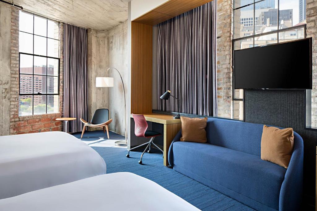 a hotel room with a bed and a couch and a tv at Aloft Dallas Downtown in Dallas