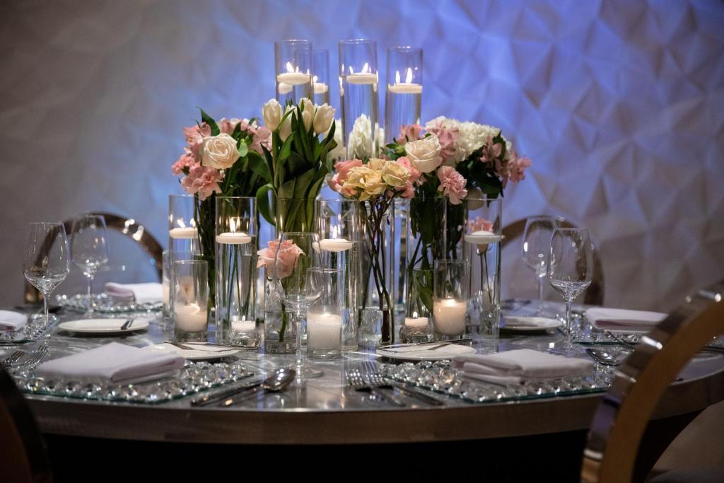 a table with candles and flowers in glass vases at Aloft Dallas Downtown in Dallas