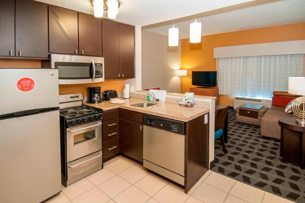 een keuken met roestvrijstalen apparatuur en een woonkamer bij TownePlace Suites by Marriott Baton Rouge Gonzales in Gonzales