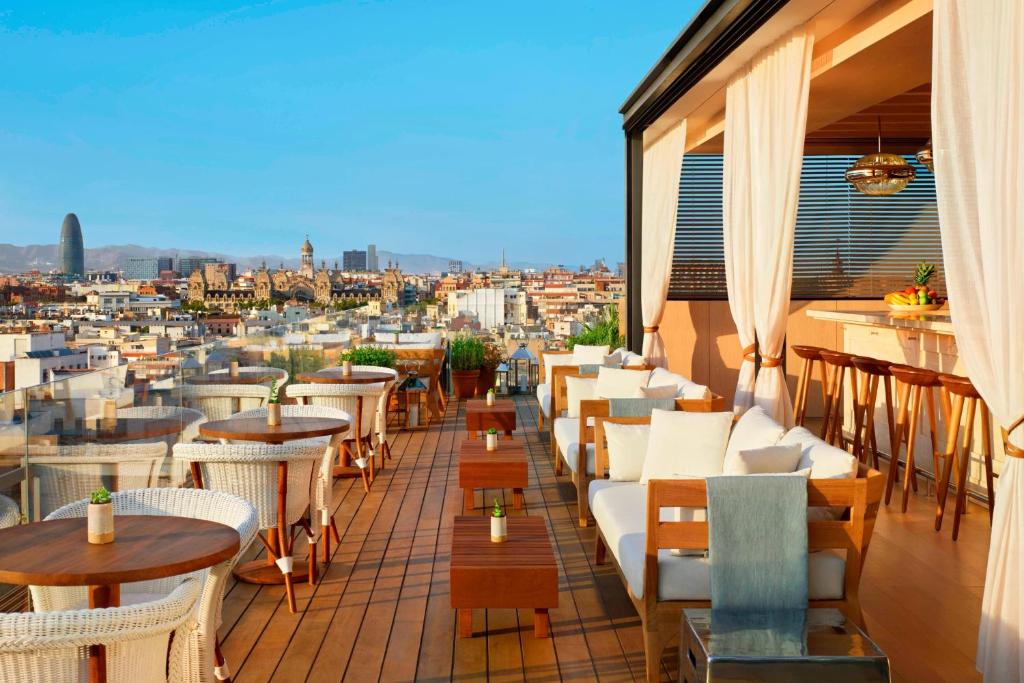 a balcony with tables and chairs and a view of a city at The Barcelona EDITION in Barcelona