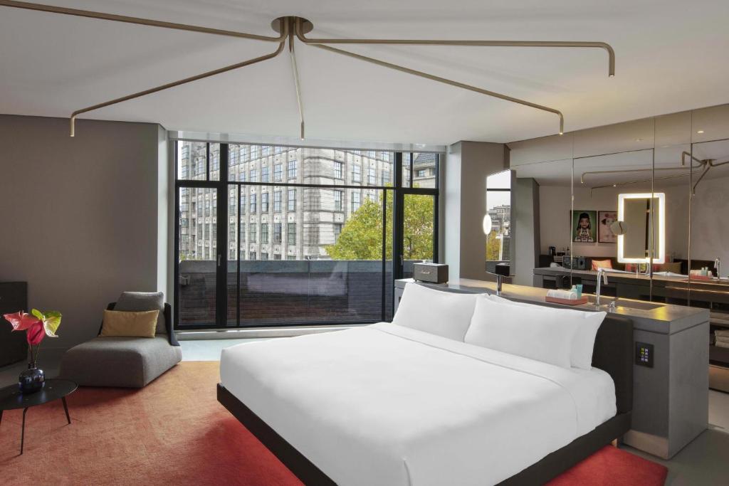 a bedroom with a large white bed and a kitchen at W Amsterdam in Amsterdam