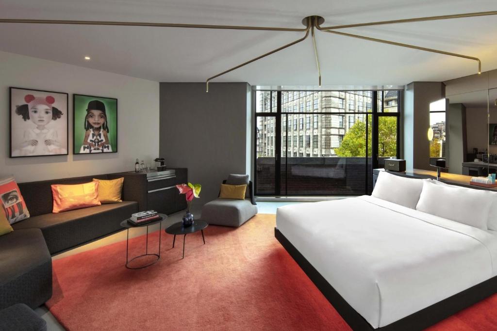 a bedroom with a large white bed and a couch at W Amsterdam in Amsterdam