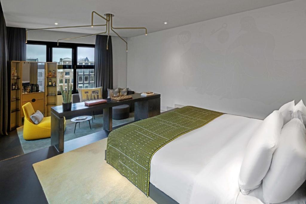 a bedroom with a bed and a desk with a yellow chair at W Amsterdam in Amsterdam