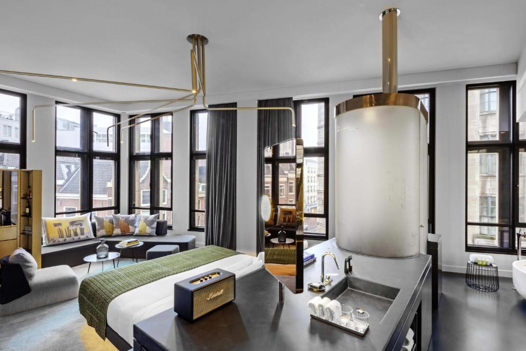 a bedroom with a bed and a living room with windows at W Amsterdam in Amsterdam