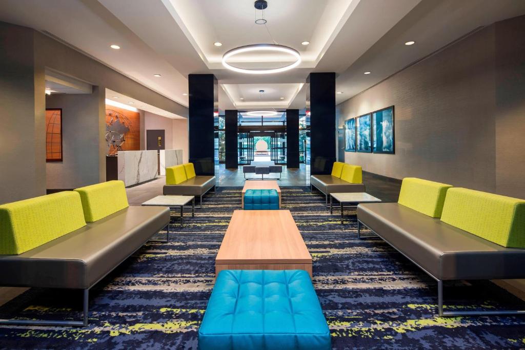 Sheraton Suites Philadelphia Airport في فيلادلفيا: غرفة انتظار وكراسي صفراء وزرقاء وطاولة
