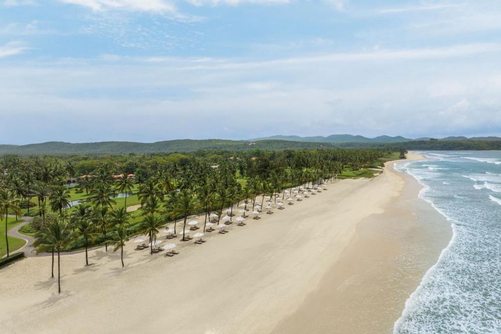 an aerial view of a beach with palm trees and the ocean at The St. Regis Goa Resort in Cavelossim