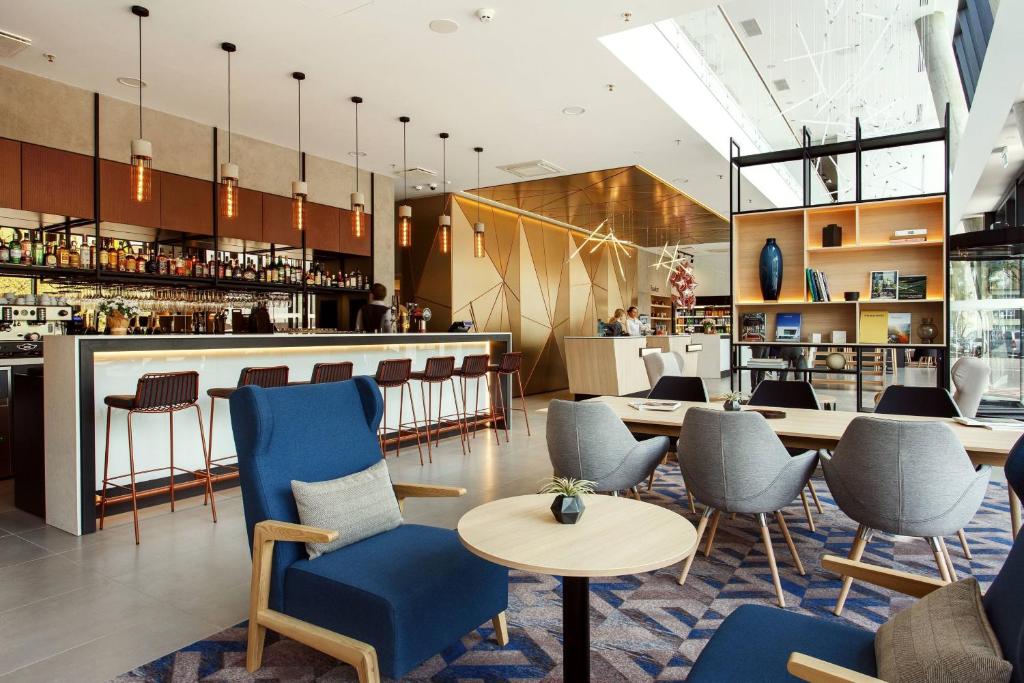 un restaurante con sillas azules y un bar en Courtyard by Marriott Vilnius City Center en Vilna