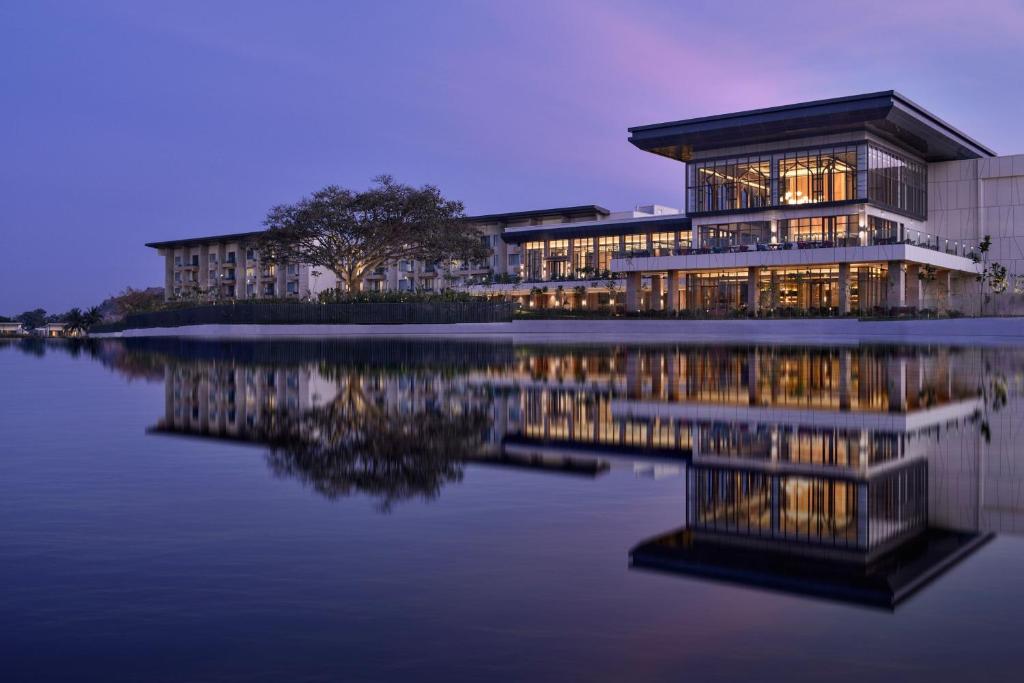 un edificio con su reflejo en el agua por la noche en JW Marriott Hotel Bengaluru Prestige Golfshire Resort & Spa, en Bangalore