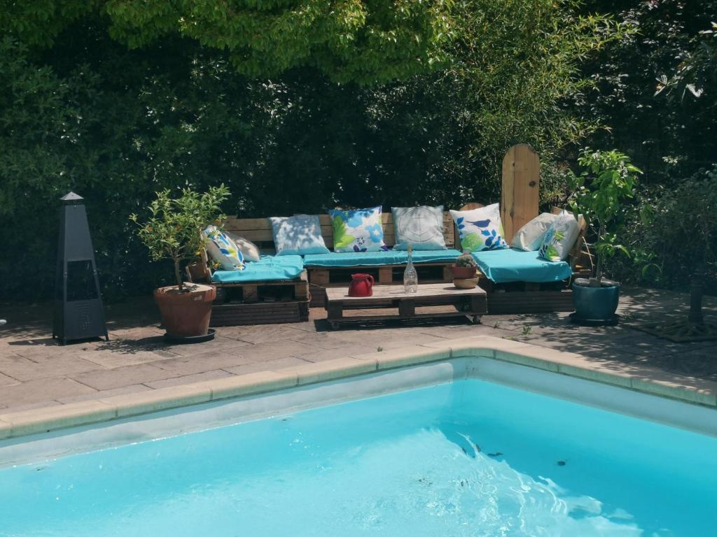 a swimming pool with a couch and a couch at Gîte effet d’art in Saint-Privat