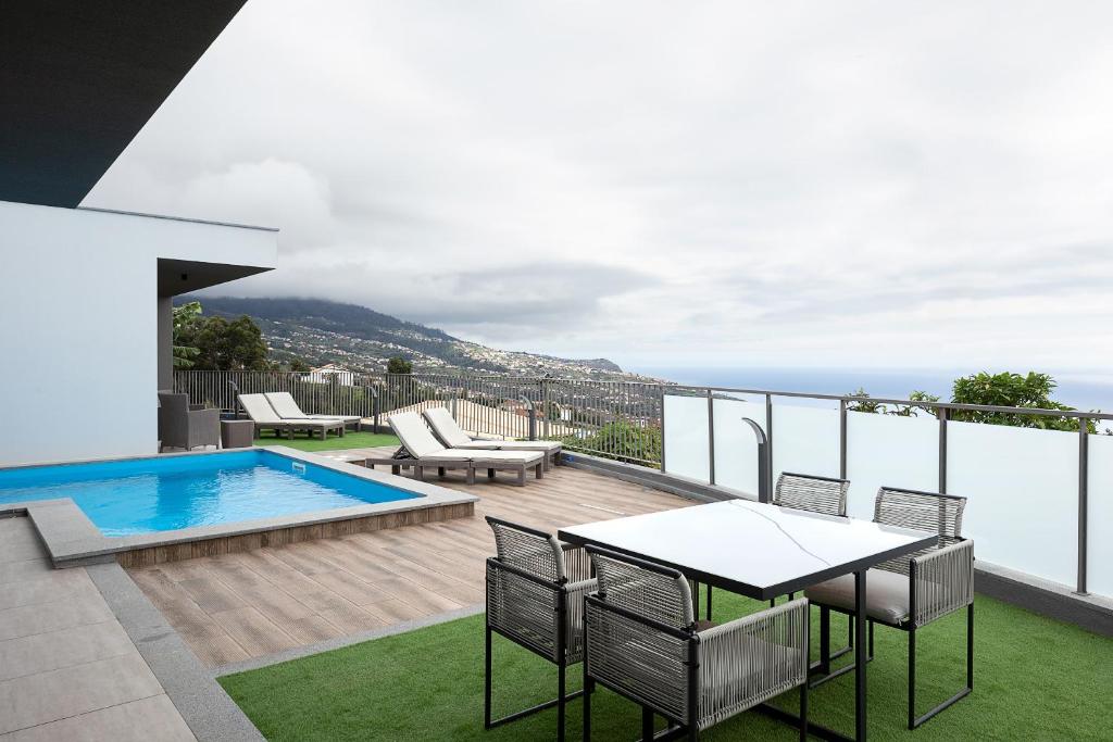 a balcony with a table and chairs and a swimming pool at King´s Paradise (Heated Pool and Sea View) in Estreito da Calheta