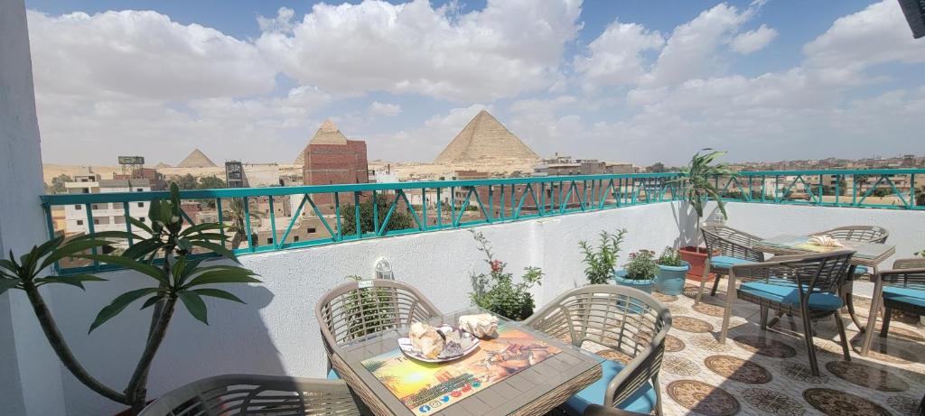 uma varanda com mesa e cadeiras e vista para as pirâmides em Pyramids Temple Guest House no Cairo