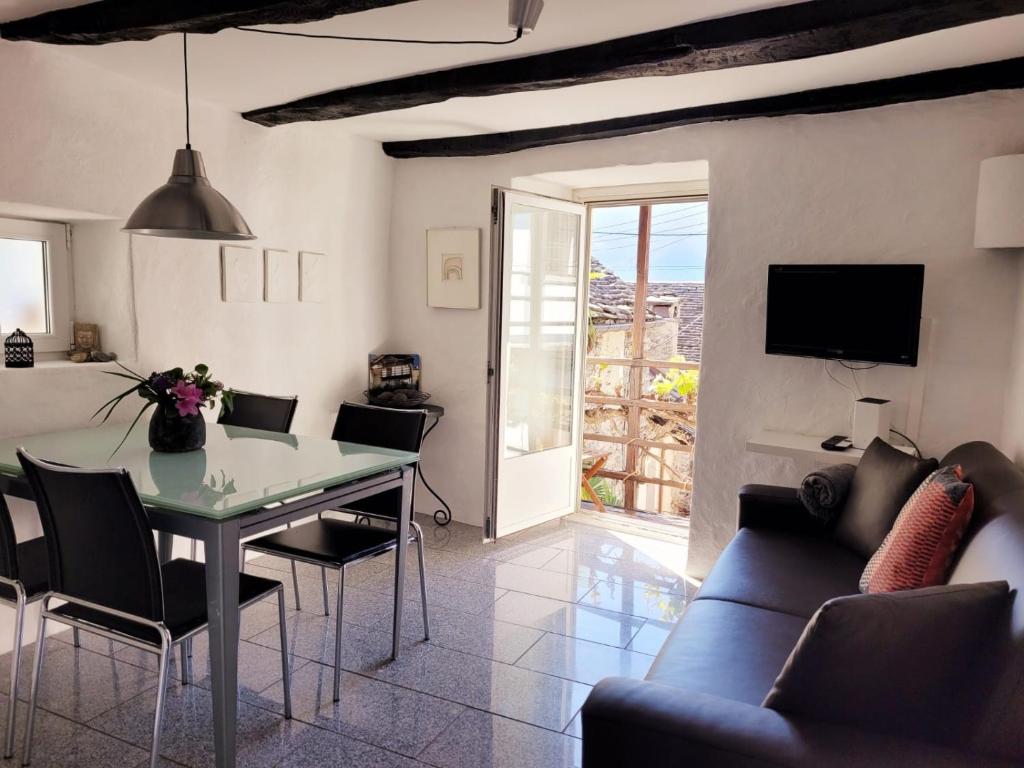 ein Wohnzimmer mit einem Tisch, Stühlen und einem TV in der Unterkunft Casa Grillino in Brione sopra Minusio