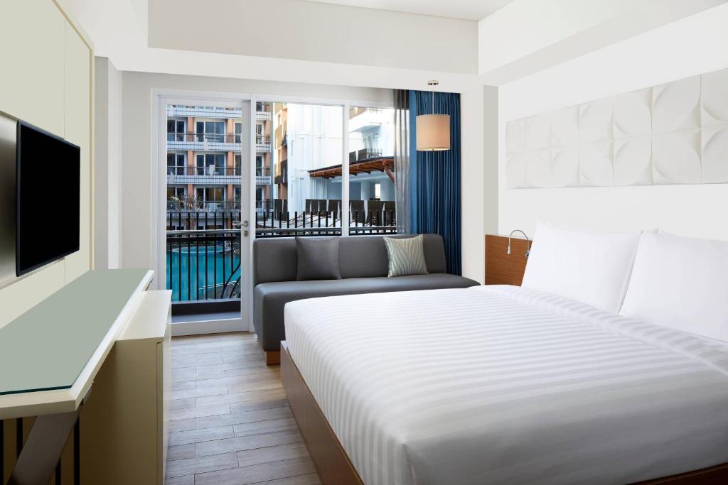 a hotel room with a bed and a couch at Fairfield by Marriott Bali Kuta Sunset Road in Kuta