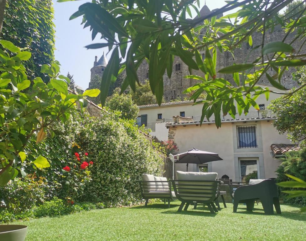 um jardim com cadeiras e um guarda-sol e um edifício em Le Cellier de Beaulieu, au pied de la Cité, Maison de Vacances avec Climatisation et Jacuzzi em Carcassonne