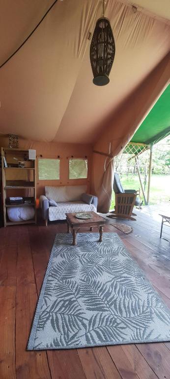 a room with a bed and a rug in a tent at La lodge du Refuge in Valigny
