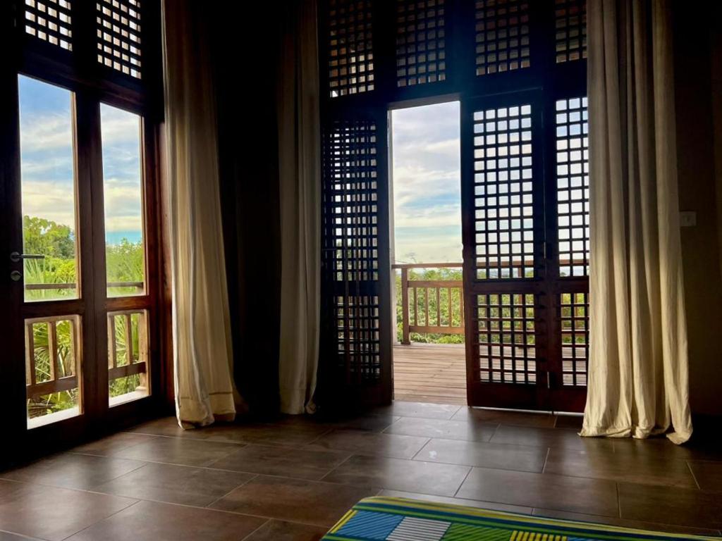 una puerta abierta a una habitación con ventanas grandes en Porini House, en Dar es Salaam