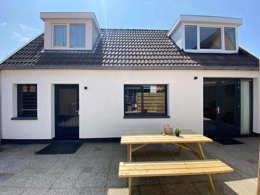 a white house with a picnic table in front of it at The island life beach house 2 in De Koog