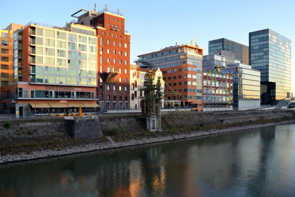 eine Stadt mit hohen Gebäuden neben einem Fluss in der Unterkunft Courtyard by Marriott Duesseldorf Hafen in Düsseldorf