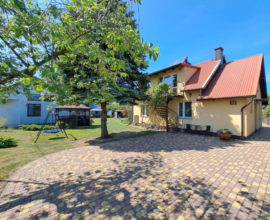 une maison avec un arbre et une allée en briques dans l'établissement Pokoje nad morzem Mikoszewo, à Mikoszewo