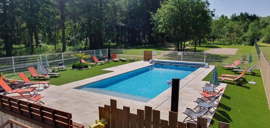 una piscina en un patio con sillas y una valla en ENTRE LOIRE ET CHER Gîte "Le Nid Douillet", en Tour-en-Sologne