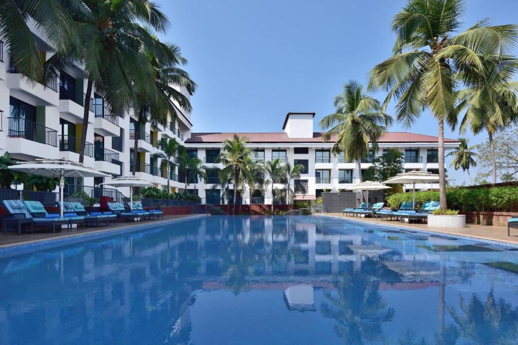einen Pool mit Palmen und Gebäuden in der Unterkunft Fairfield by Marriott Goa Anjuna in Anjuna