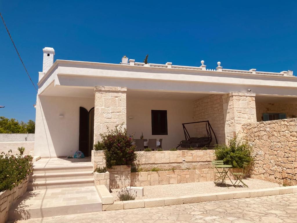 a small white house with a stone wall at La Racioppola in Ostuni