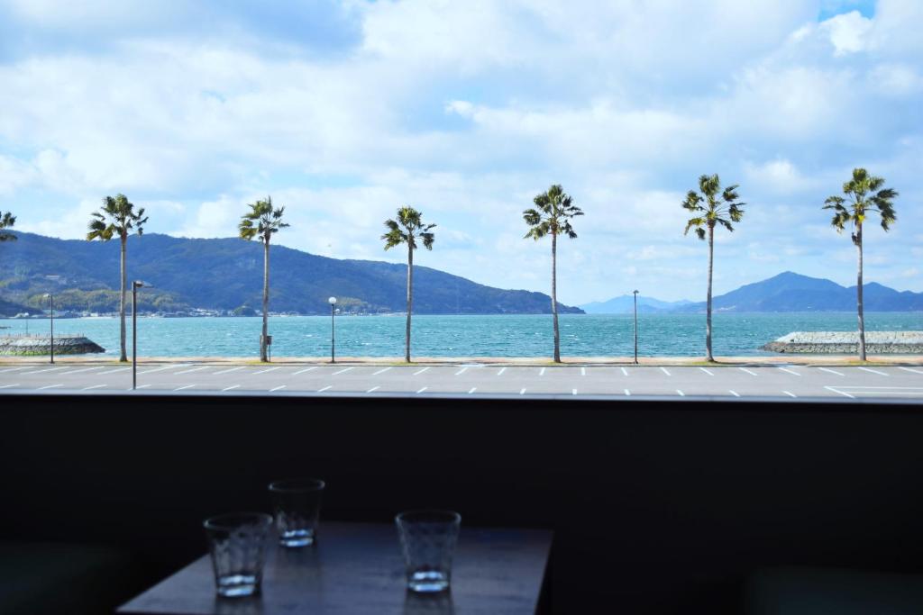 a view of the ocean from a restaurant with palm trees at 伯方plus+ in Imabari