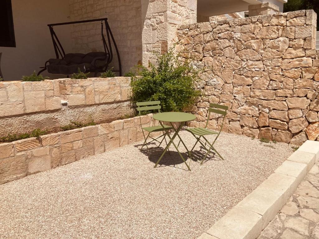 a table and two chairs in front of a stone wall at La Racioppola in Ostuni
