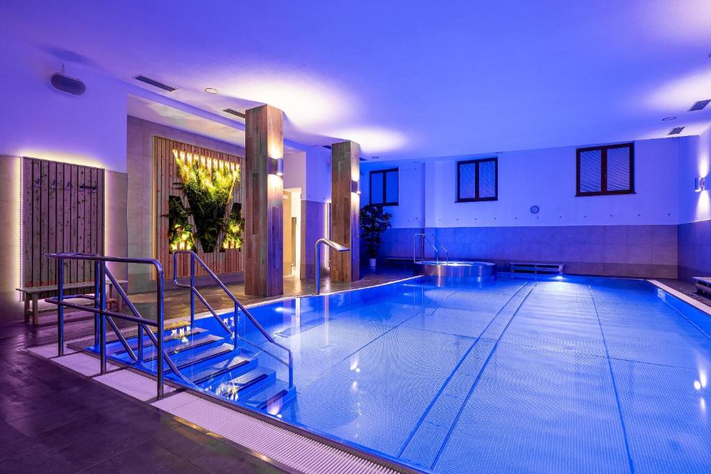 een groot zwembad met blauwe verlichting in een gebouw bij Wellness Hotel pod Kyčmolem in Horní Lomná