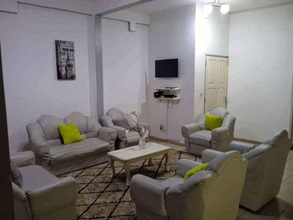 a living room with couches and chairs and a tv at Cybhouse in Yaoundé