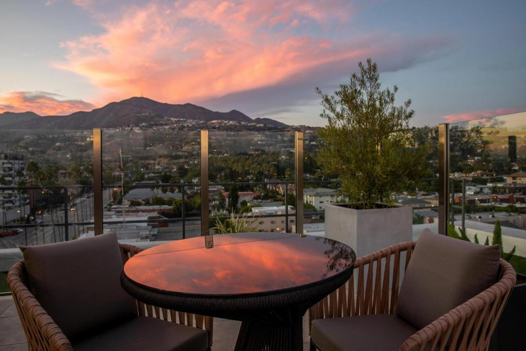 a table and chairs on a balcony with a view of a city at The Glenmark, Glendale, a Tribute Portfolio Hotel in Glendale