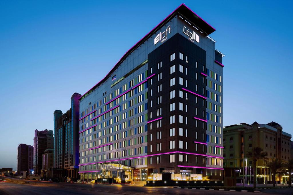 een hoog zwart gebouw met paarse lichten erop bij Aloft Dhahran Hotel in Al Khobar