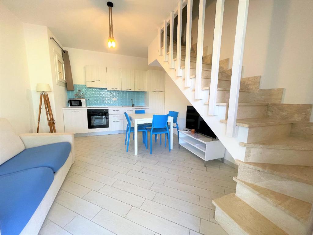 a kitchen and dining room with a table and blue chairs at Affittimoderni Viddalba Bouganville - VIBO11 in Viddalba